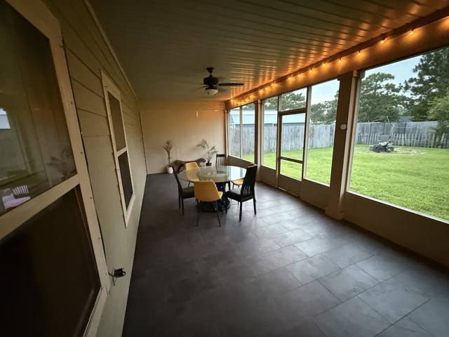 Screened back porch with dining table and string lights